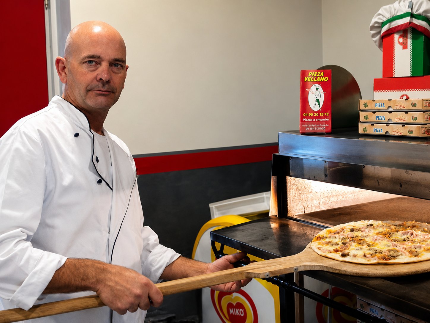 Jean-Marc sortant une pizza du four à l'aide d'une pelle en bois